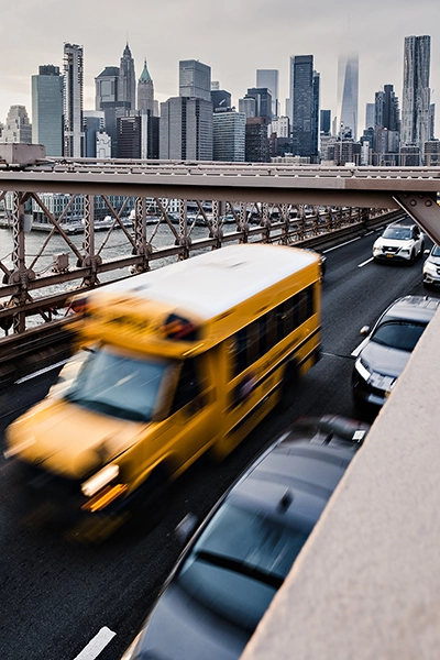 A shot of a busy city bridge prominently featuring a yellow school bus taken using long exposure photography to create a sense of motion.