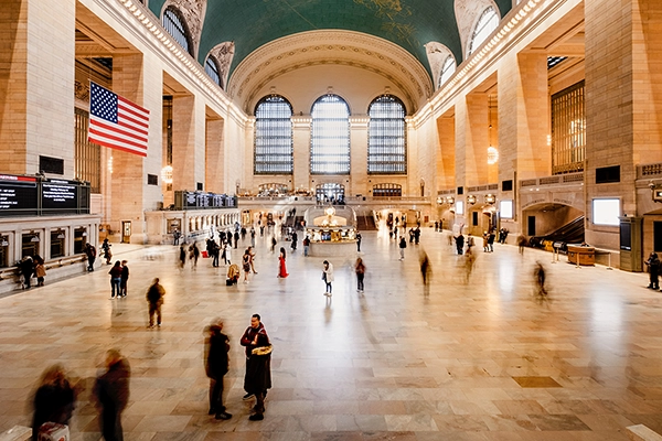 A spacious train station filled with people photographed using long exposure photography to create a sense of bustling activity.